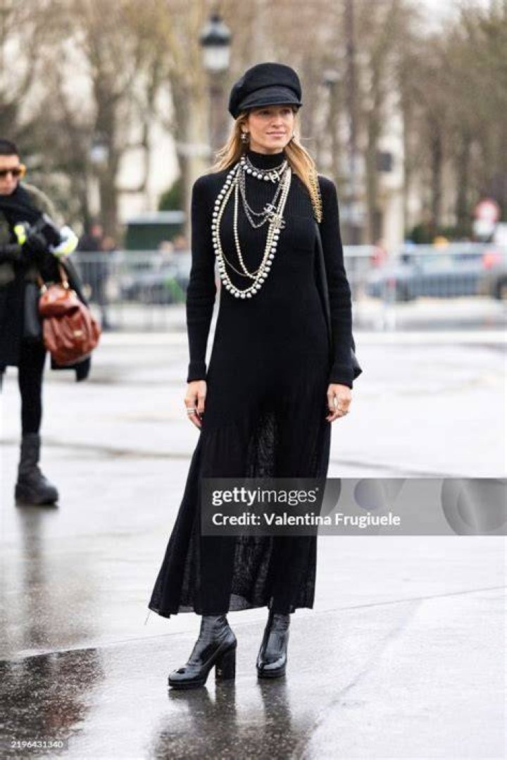 Helena Bordon wears a black decorated Chanel tank top, a Chanel tweed maxi skirt over Chanel jeans, black belt, black Chanel mini bag, black platform heels and Chanel earrings, outside Chanel, during the Haute Couture Fall/Winter 