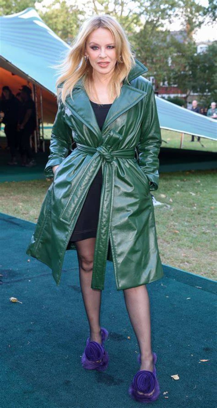 Kylie Minogue in leather coat and black mini dress
