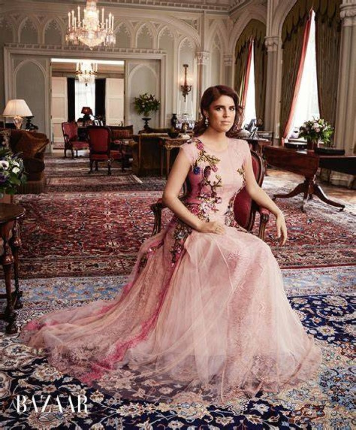 Princess Eugenie poses in a black dress in front of a creative painting
